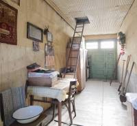 Menší rodinný dom len pár metrov od centra mesta Rajec - Interiér rodinného domu s rebríkom vedľa vyšívanej tapiserie. Podlaha s dreveným dekorom.