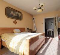 Menší rodinný dom len pár metrov od centra mesta Rajec - Spálňa v rodinnom dome s dreveným nábytkom, obrazom a lustrom.