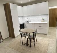 Na prenájom 1-izbový byt - Nové Zámky - Kuchyňa v 1-izbovom byte s bielymi skrinkami a jedálenským stolom.