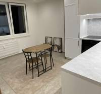 Na prenájom 1-izbový byt - Nové Zámky - Kuchyňa v 1-izbovom byte s jedálenským stolom, skriňami a dekoračnými obrazmi na stene.