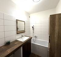 PREDAJ-  2 izbový byt neďaleko Nitry v obci Jarok - Kúpeľňa 2-izbového bytu so svetlými obkladačkami, vaňou a dreveným nábytkom.