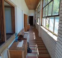 Na predaj  dom v obci Vyhne iba 400m od Vodného raja.  - Presvetlená zimná záhrada s dlažbou v rodinnom dome na ulici Vyhne, drevená lavica.