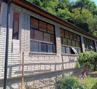 Na predaj  dom v obci Vyhne iba 400m od Vodného raja.  - Dom na ulici Vyhne s presklenou verandou a kamenným základom, obklopený zeleňou.