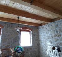 Štýlový rekreačný domček Levice - Kamenné steny chaty s dreveným stropom, dvomi oknami a prútenými stoličkami.