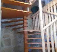 Štýlový rekreačný domček Levice - Interiér chaty so schodiskom z dreva a kamennými stenami.