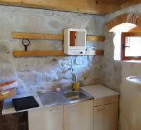 Štýlový rekreačný domček Levice - Vidiecka kuchynka v chate s kamennými stenami a drevenými detailmi.