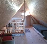 Štýlový rekreačný domček Levice - Podkrovný priestor chaty s dreveným dekorom, dvoma matracmi a kreslom.