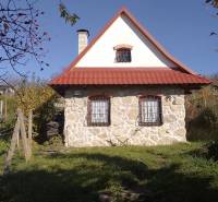 Štýlový rekreačný domček Levice - Klasická kamenná chata v Starých Leviciach, rekreačná lokalita, obklopená zeleňou a dreveným plotom.