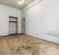 3- izb. byt o výmere 105m2 v historickom centre. - Prázdna miestnosť v 3-izbovom byte s podlahou s dreveným dekorom a bielymi stenami.