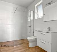 IDEÁLNY 1 IZBOVÝ BYT | VEĽKÉ RIPŇANY | TOPOĽČANY - Kúpeľňa s bielymi obkladačkami, sprchou a podlahou s dreveným dekorom v 1-izbovom byte.