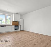 IDEÁLNY 1 IZBOVÝ BYT | VEĽKÉ RIPŇANY | TOPOĽČANY - Kuchyňa v 1-izbovom byte s bielymi skrinkami a podlahou s dreveným dekorom.