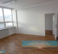 PRENÁJOM KANCELÁRSKÝCH PRIESTOROV NA RAČIANSKEJ ULICI - Svetlá miestnosť s veľkým oknom, drevenou podlahou a radiátorom v lokalite Račianska.