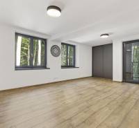 PREDAJ 8 IZB.REKREAČNEJ CHATY - VILY V MODRE HARMÓNII - Priestranná miestnosť s drevenou podlahou, veľkými oknami a výhľadom do lesa.