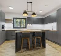 PREDAJ 8 IZB.REKREAČNEJ CHATY - VILY V MODRE HARMÓNII - Kuchyňa s tmavými skrinkami, drevenou podlahou, barovými stoličkami, na ulici Piesok.