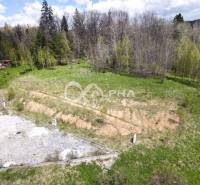Stavebné pozemky v lokalite Slnečná úboč, Levočská Dolina - Pozemok v Levočskej doline, Levoča obklopený zeleňou a mladou lesnou vegetáciou.