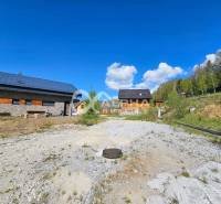 Stavebné pozemky v lokalite Slnečná úboč, Levočská Dolina - Levočská dolina, Levoča: Pozemky - bývanie. Vidiecky dom obklopený lesom a modrou oblohou.