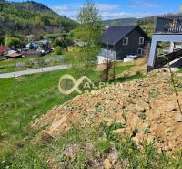 Stavebný pozemok lokalita Slnečná úboč, Levočská Dolina, okres Levoča - Pozemky - bývanie v Levoči s domami na svahovitej krajine, obklopené zeleňou.