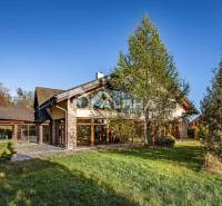 Exkluzívny rodinný dom, Veľká Lomnica, okres Kežmarok - Rodinný dom vo Veľkej Lomnici obklopuje zeleň, s kamennou fasádou a stromami v okolí.