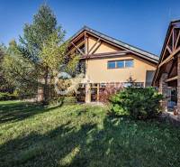 Exkluzívny rodinný dom, Veľká Lomnica, okres Kežmarok - Rodinný dom vo Veľkej Lomnici s trávnatou záhradou, obklopený stromami a kamenitou fasádou.