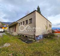 Budova s pozemkom, obec Helcmanovce, okres Gelnica - Budova v Helcmanovciach s trávnatým okolím a susednými domami, obklopená kopcami.