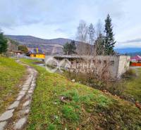 Budova s pozemkom, obec Helcmanovce, okres Gelnica - Budova v Helcmanovciach, obklopená kopcami a cestou s trávnikom a stromami.