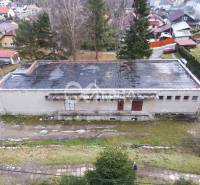 Budova s pozemkom, obec Helcmanovce, okres Gelnica - Budova v Helcmanovciach so šikmou strechou, obklopená zeleňou a ďalšími stavbami.