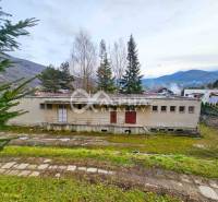 Budova s pozemkom, obec Helcmanovce, okres Gelnica - Budova v Helcmanovciach obklopená prírodou s kopcami v pozadí.