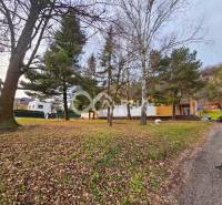 Budova s pozemkom, obec Helcmanovce, okres Gelnica - Budova v Helcmanovciach obklopená stromami, popri asfaltovej ceste, s jesenným lístím.