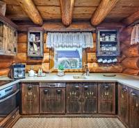 Zrubový rodinný dom, Veľká Lomnica - Rustikálna kuchyňa v rodinnom dome s drevenými skrinkami a pohľadom z okna.