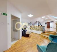 Prenájom priestorov, centrum, Spišská Nová Ves - Interiér kancelárie s podlahou s dreveným dekorom, kamennými stenami a pohodlnými stoličkami.