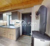 Exkluzívne záhradná chata, sídlisko Tarča, Spišská Nová Ves - Kuchyňa v chate s podlahou s dreveným dekorom, sporákom a svetlými skrinkami.