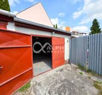 Prenájom garáž, centrum, Spišská Nová Ves - Otvorené garáže v Spišskej Novej Vsi s červenými dverami a plechovým plotom.