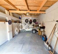 Prenájom garáž, centrum, Spišská Nová Ves - Garáže v Spišskej Novej Vsi s prívesným vozíkom, policami a náradím na stene.