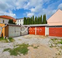 Prenájom garáž, centrum, Spišská Nová Ves - Garáže v Spišskej Novej Vsi, štrková príjazdová cesta, budovy v pozadí, cyprusy.