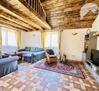 Vám ponúka na predaj rodinný dom v Komárne, ča - Obývačka v rodinnom dome s podlahou s dreveným dekorom, pohovkami a televíziou.