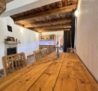Vám ponúka na predaj rodinný dom v Komárne, ča - Interiér rodinného domu so stolom z drevom dekoru, krbom a dreveným stropom.
