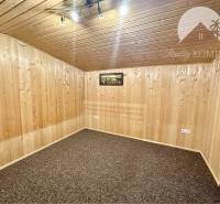 Vám ponúka na predaj rodinný dom v Komárne, ča - Izba v rodinnom dome s drevom obloženými stenami a kobercovou podlahou.
