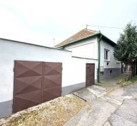IBA U NÁS !!! ponúka EXKLUZÍVNE na predaj rodin - Rodinný dom v Komárne so zelenými detailami a hnedou bránou na tichej ulici.