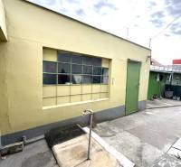 IBA U NÁS !!! ponúka EXKLUZÍVNE na predaj rodin - Exteriér rodinného domu v Komárne so žltou stenou a zelenými dverami.