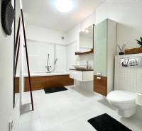 Vám EXKLUZÍVNE ponúka NA PRENÁJOM moderný 2 iz - Kúpeľňa v 2-izbovom byte s vaňou, umývadlom a toaletou na bielej dlažbe.