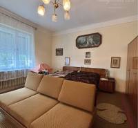 Vám ponúka na predaj 4 izbový rodinný dom  s r - Obývacia izba v rodinnom dome s pohovkou, lustrom a svetlou záclonou na okne.