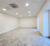 Vám ponúka  na predaj budovu na BÝVANIE aj PODN - Priestranná izba s dlažbou, biele steny, zasadená v útulnej budove.