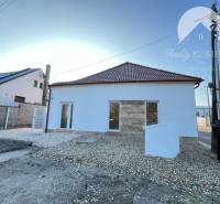 Vám ponúka  na predaj budovu na BÝVANIE aj PODN - Dom s bielou fasádou, šikmou strechou, oknami a bielym kamienkovým chodníkom pred ním.