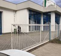 Vám ponúka do PRENÁJMU priestranné a slnečné ob - Obchodné priestory na ulici 1. mája v Hurbanove s modrými oknami za bielym plotom.