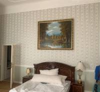 Vám ponúka do PRENÁJMU čarovný, úplne zrekonštr - Spálňa v rodinnom dome s posteľou, lustrom a jemnou tapetou, podlaha s dreveným dekorom.