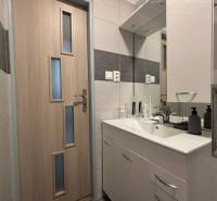 Vám ponúka exkluzívne na predaj moderný, komple - Kúpeľňa v 1-izbovom byte s umývadlom, zrkadlom a drevenými dverami.