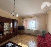 Reality KOMPLEX Vám ponúka EXKLUZÍVNE na predaj rodinný dom, ktorý sa  - Obývacia izba v rodinnom dome s podlahou s dreveným dekorom, tmavým nábytkom a červenou pohovkou.