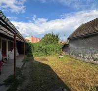 Reality KOMPLEX Vám ponúka EXKLUZÍVNE na predaj rodinný dom, ktorý sa  - Dvor rodinného domu vo Veľkom Mederi s viditeľnými strechami dvoch budov.