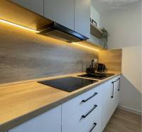 Vám ponúka na Prenájom 2-izbový byt s loggiou  - Kuchyňa v 2-izbovom byte s podlahou s dreveným dekorom a zabudovanými skrinkami.