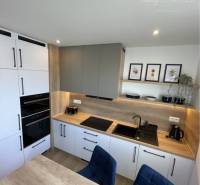 Vám ponúka na Prenájom 2-izbový byt s loggiou  - Kuchyňa v 2-izbovom byte s dreveným dekorom na pracovnej doske a podlahe.